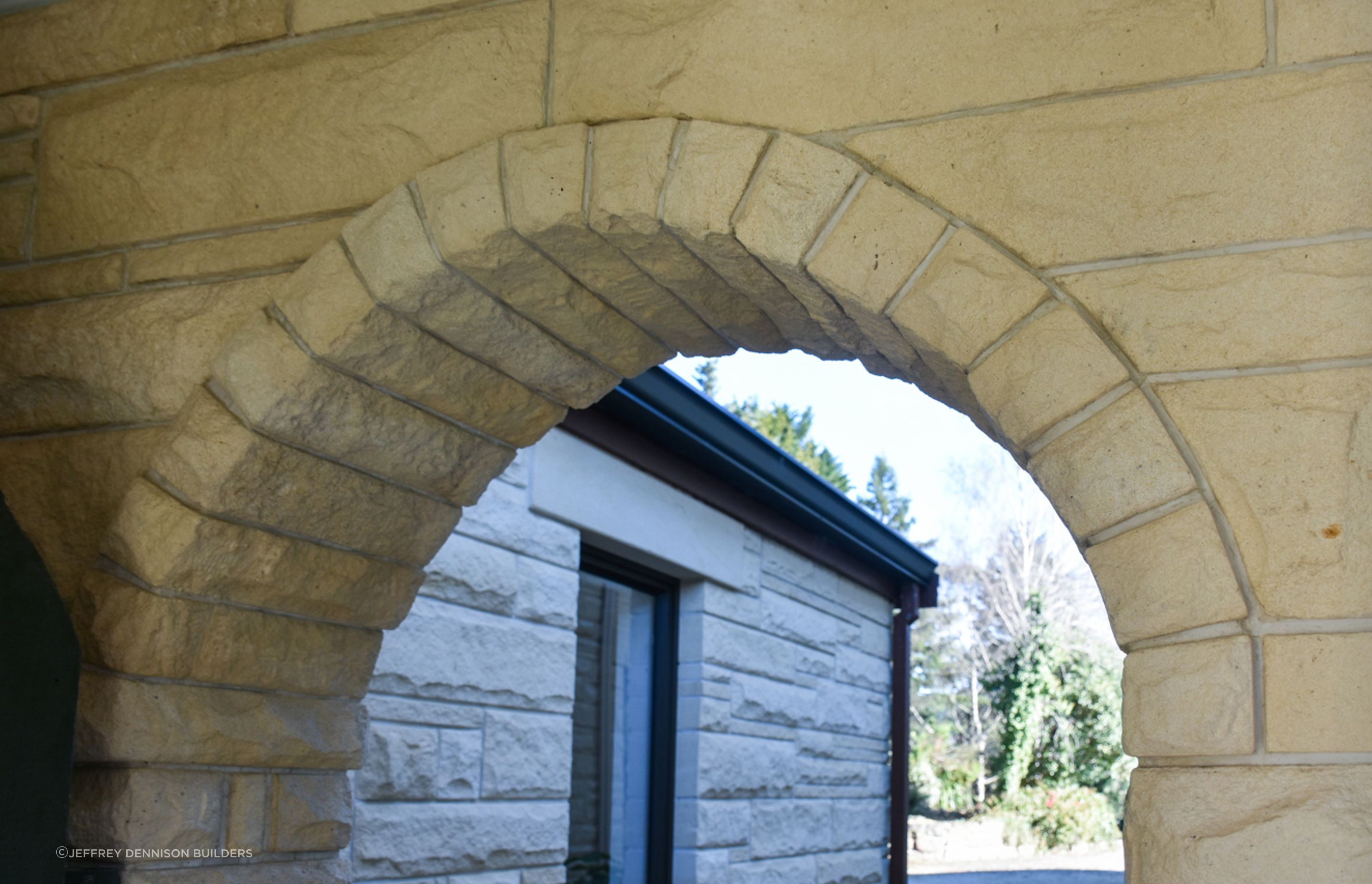 Close up of the cleaned/restored Oamaru stone arch with a view towards the garage and drive