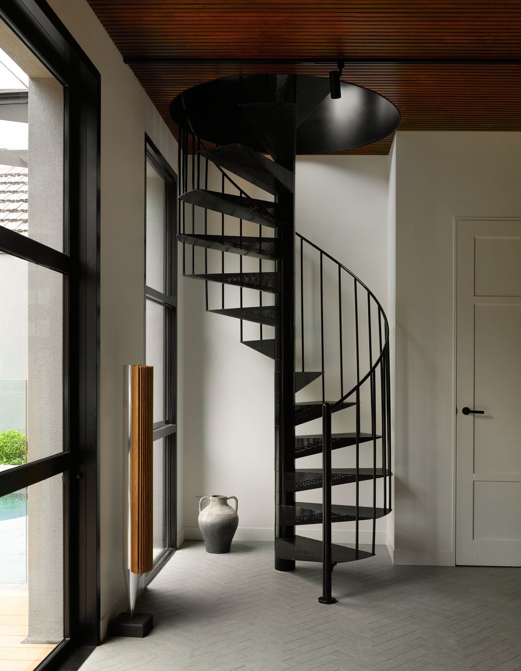 At the rear, a compact spiral staircase adds sculptural interest while linking the upper levels to a stunning outdoor retreat complete with pool, fireplace, and alfresco zones designed for year-round enjoyment.