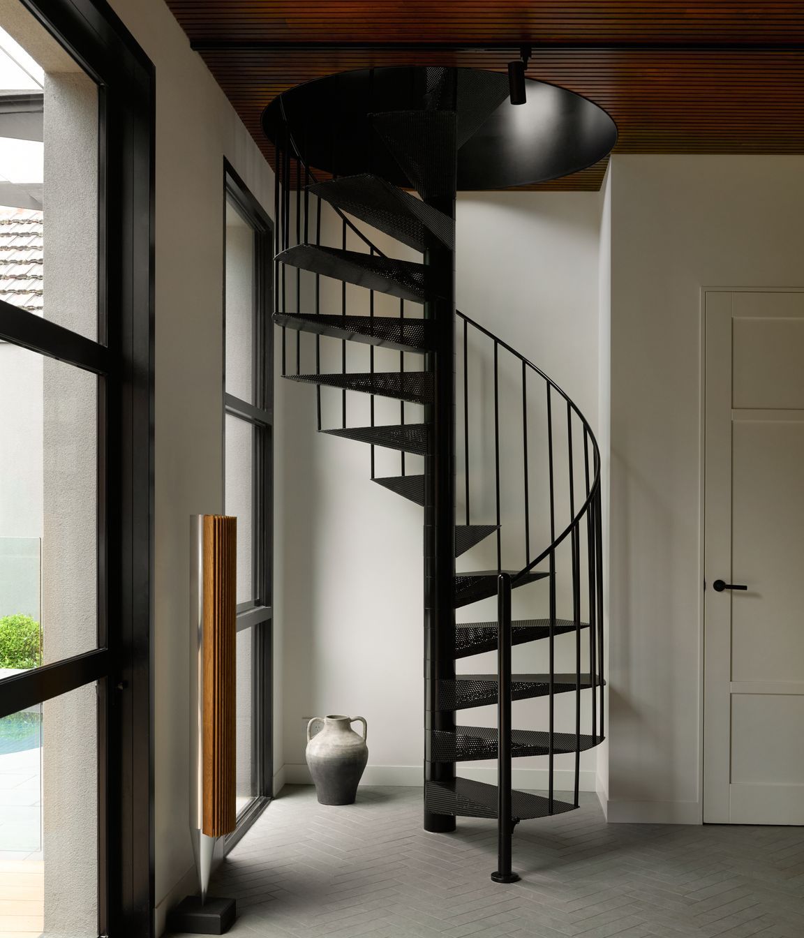 At the rear, a compact spiral staircase adds sculptural interest while linking the upper levels to a stunning outdoor retreat complete with pool, fireplace, and alfresco zones designed for year-round enjoyment.