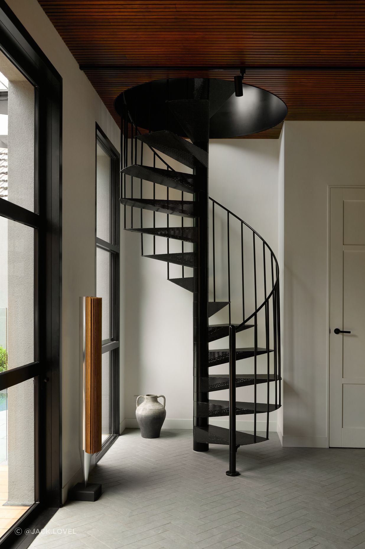 At the rear, a compact spiral staircase adds sculptural interest while linking the upper levels to a stunning outdoor retreat complete with pool, fireplace, and alfresco zones designed for year-round enjoyment.