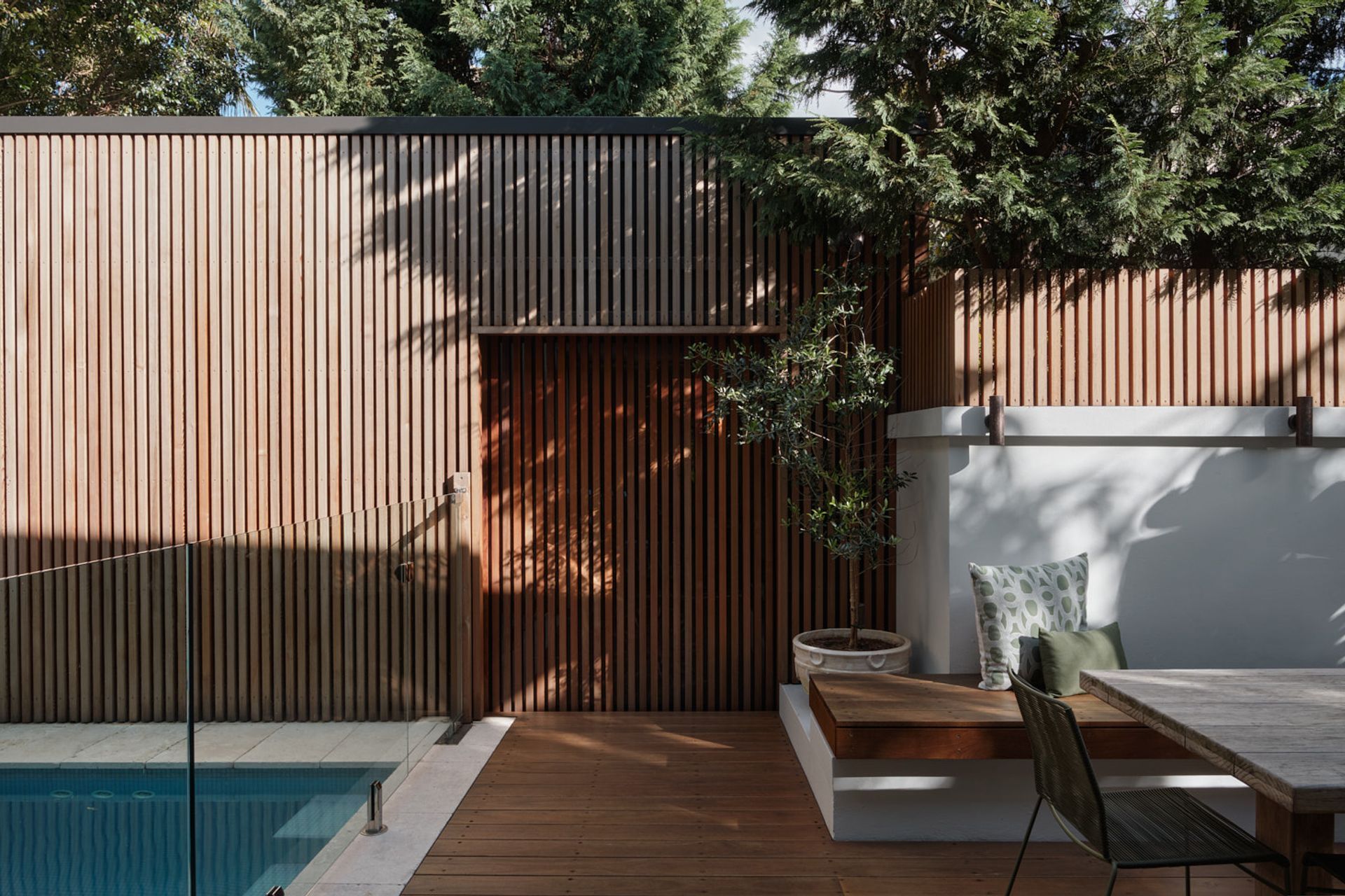 The detached garage is accessed through a sliding door via the rear outdoor space. The vertical timber layer on the door, matching the enclosure of the of the garage provides a visual concealment.