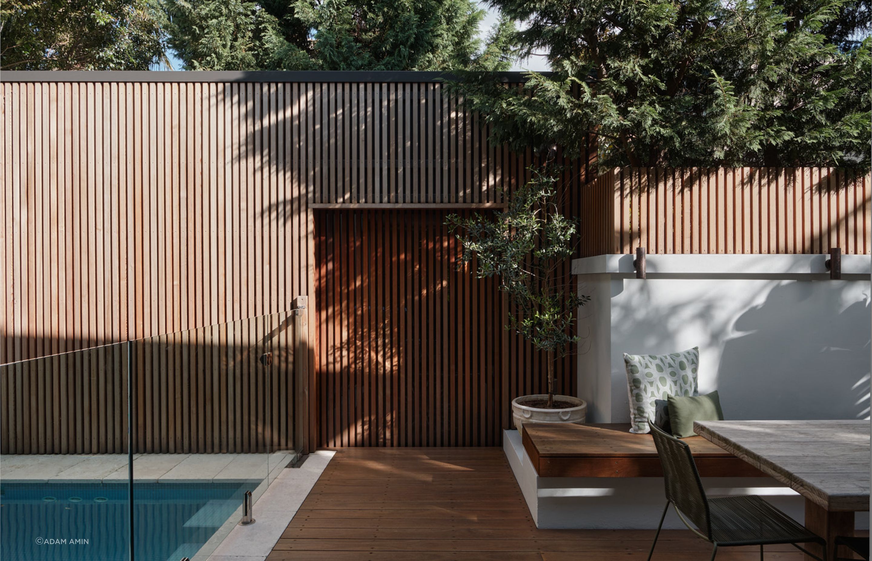 The detached garage is accessed through a sliding door via the rear outdoor space. The vertical timber layer on the door, matching the enclosure of the of the garage provides a visual concealment.