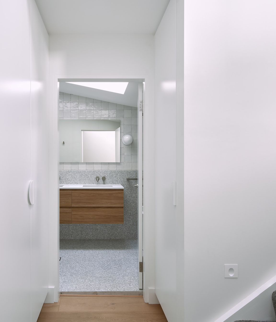 The entry to the shared bathroom, located in the transitional zone of the home, is graced with custom joinery, maximising the space available.