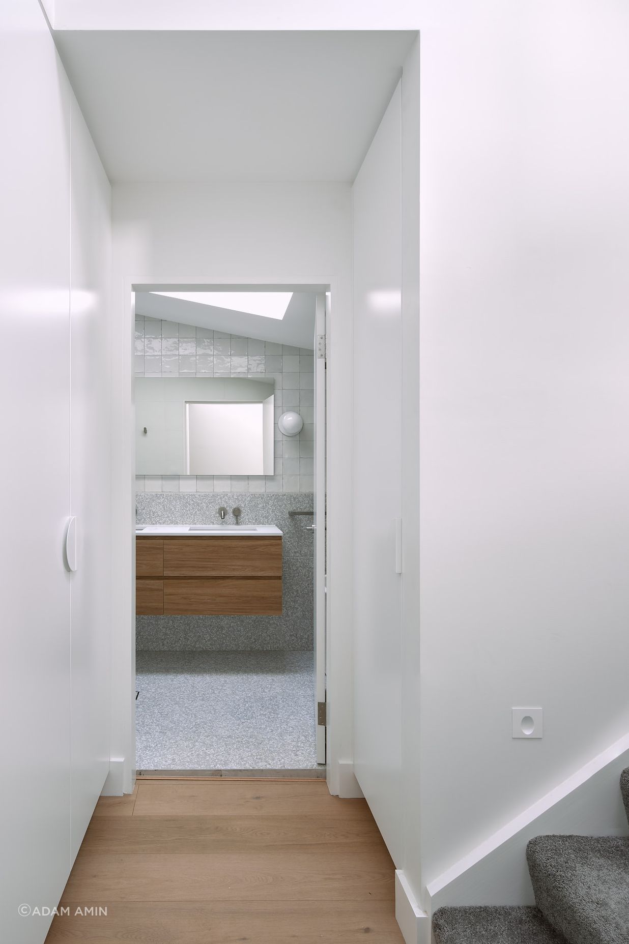 The entry to the shared bathroom, located in the transitional zone of the home, is graced with custom joinery, maximising the space available.