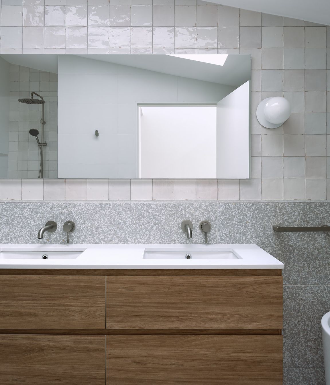 Materials with neutral tones are contrasted with darker pallet natural materials. Maximising texture allows a gradient of tones on light colour materials caused by the overhead skylight.