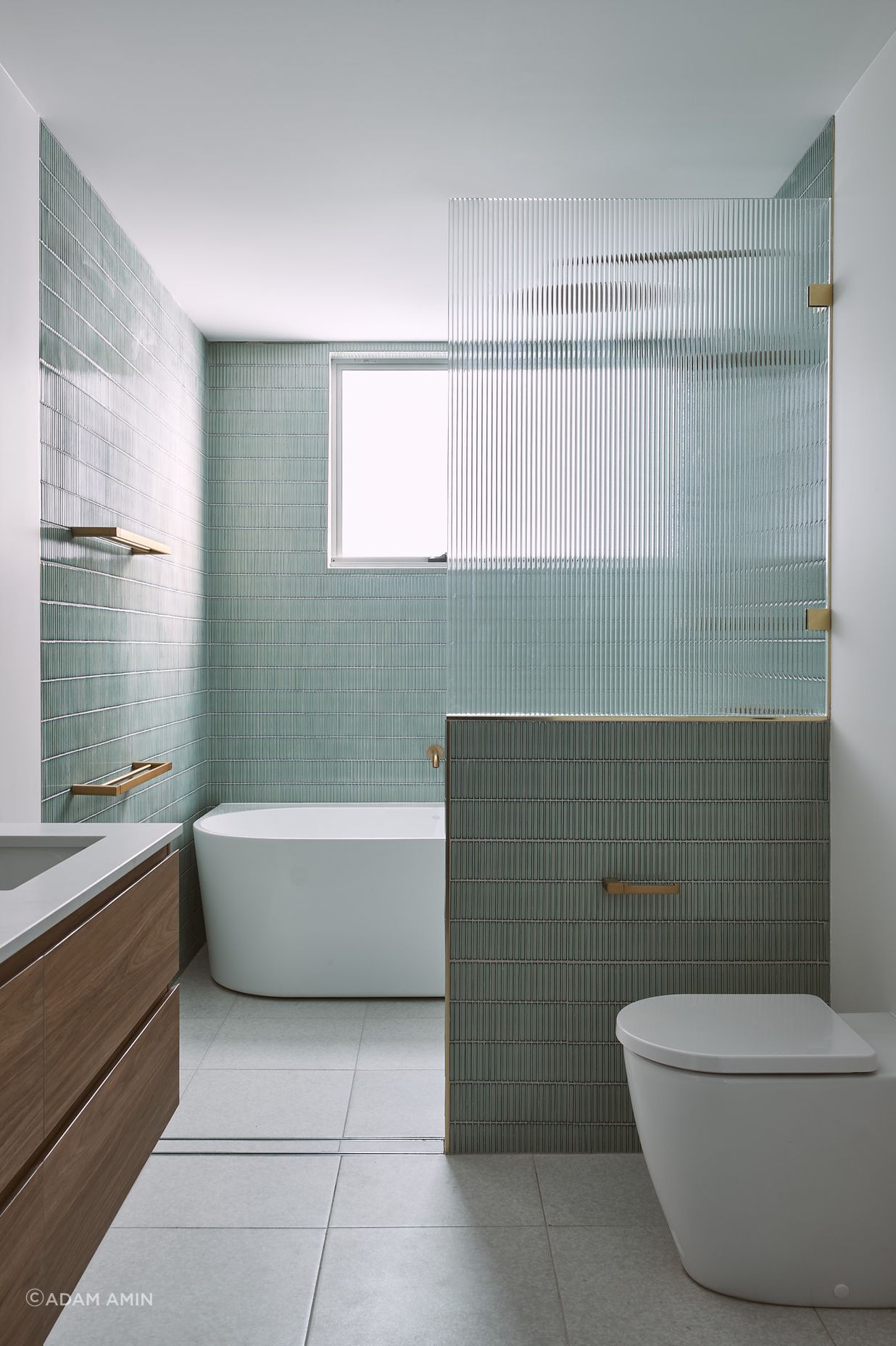 Green finger tiles and fluted glass cut the ensuite to a different class. Brass fixtures and ornate lights embellish the private bathroom.