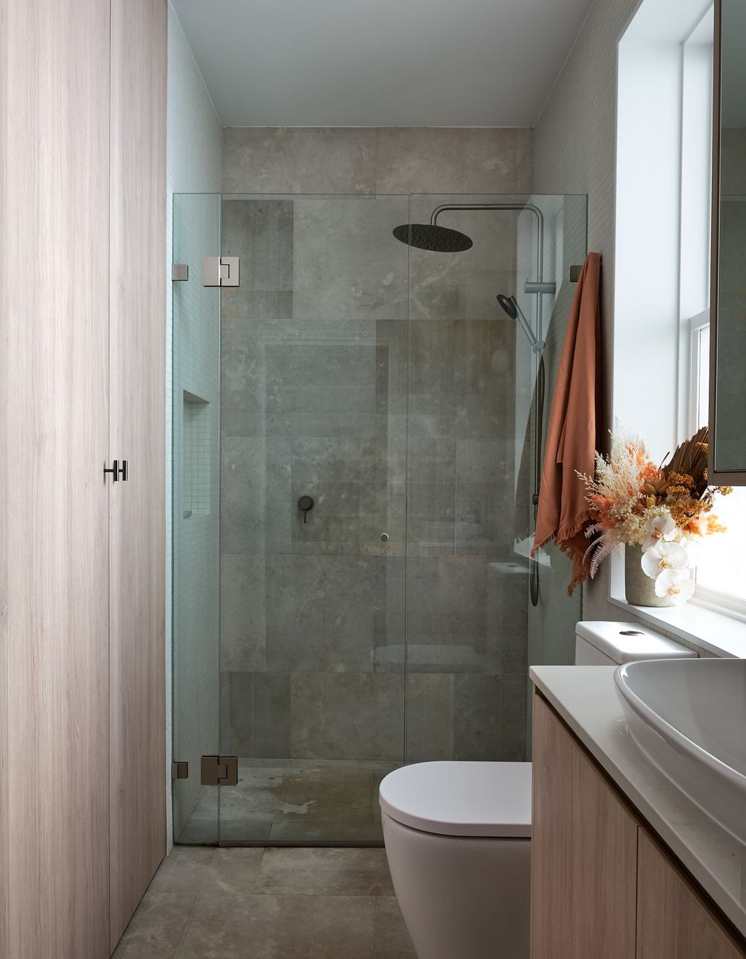 The shared bathroom takes advantage of its location and access to preinstalled services. Sharing footprint, the space underneath the stairs is further utilised as laundry, and storage space, concealed behind seamless joinery accessed through the bathroom.