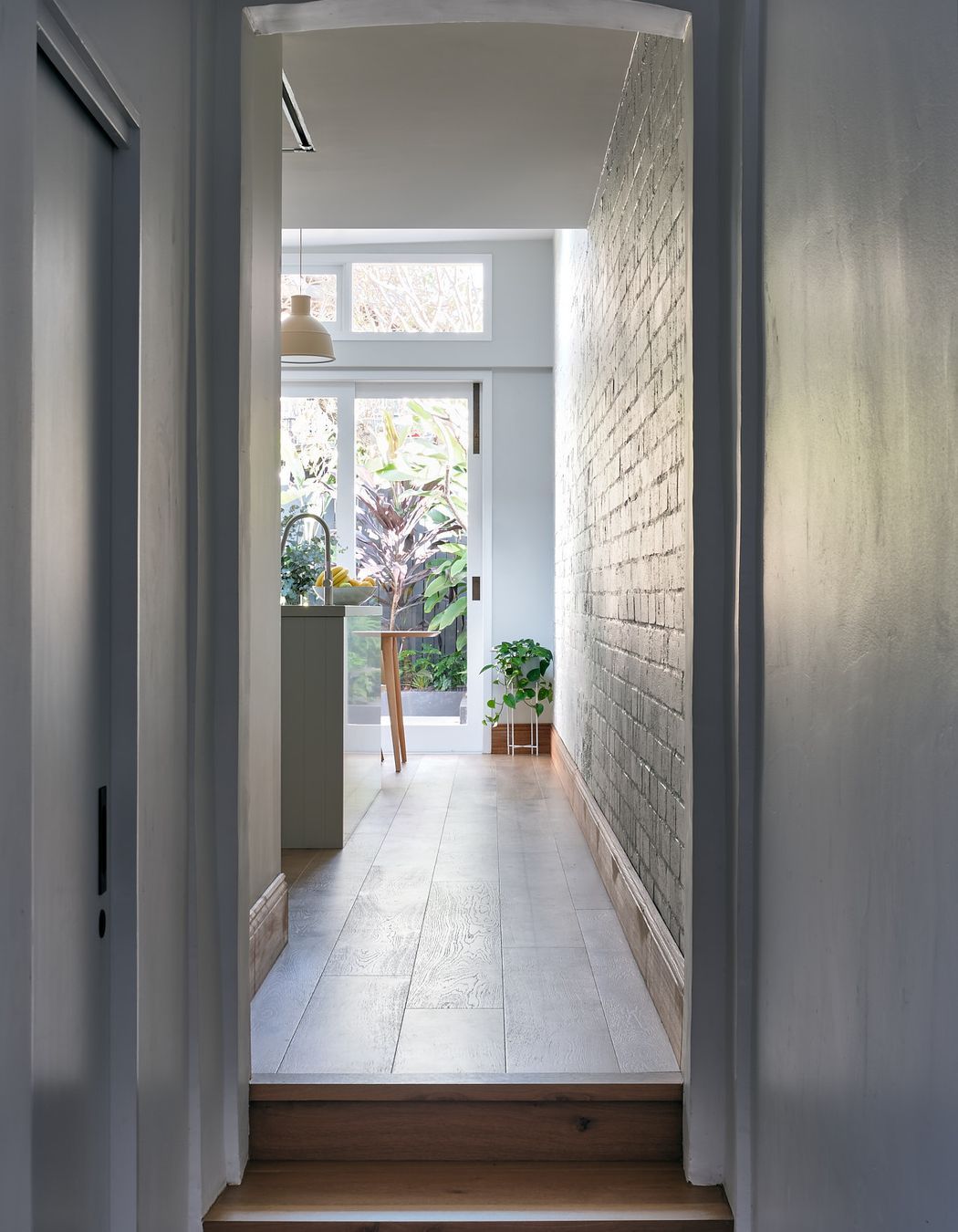 The narrow hallway leading to the home's original termination is a vestibule to the light-saturated open-plan kitchen and adjacent dining spaces.