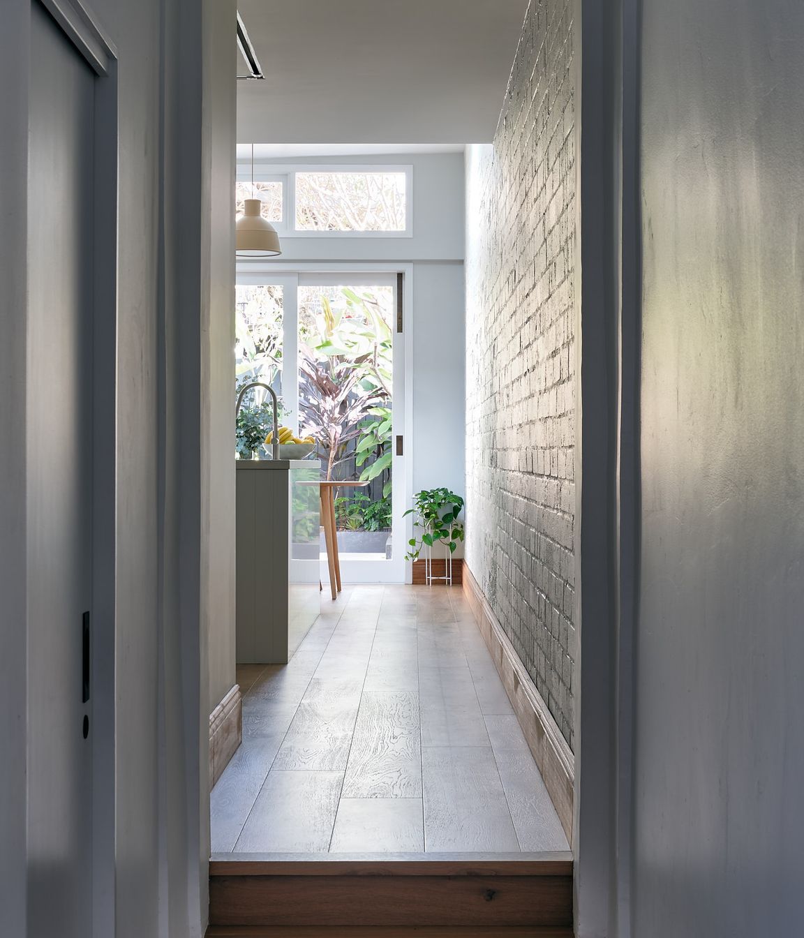 The narrow hallway leading to the home's original termination is a vestibule to the light-saturated open-plan kitchen and adjacent dining spaces.