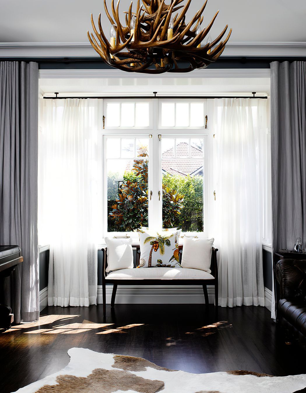 BRITISH COLONIAL STYLE LIVING ROOM - A whimsical window treatment is perfectly paired with the striking elements of this living room.