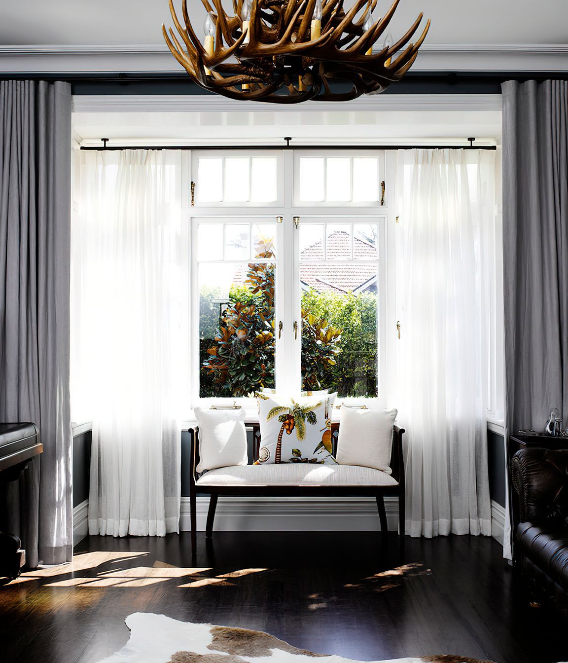 BRITISH COLONIAL STYLE LIVING ROOM - A whimsical window treatment is perfectly paired with the striking elements of this living room.