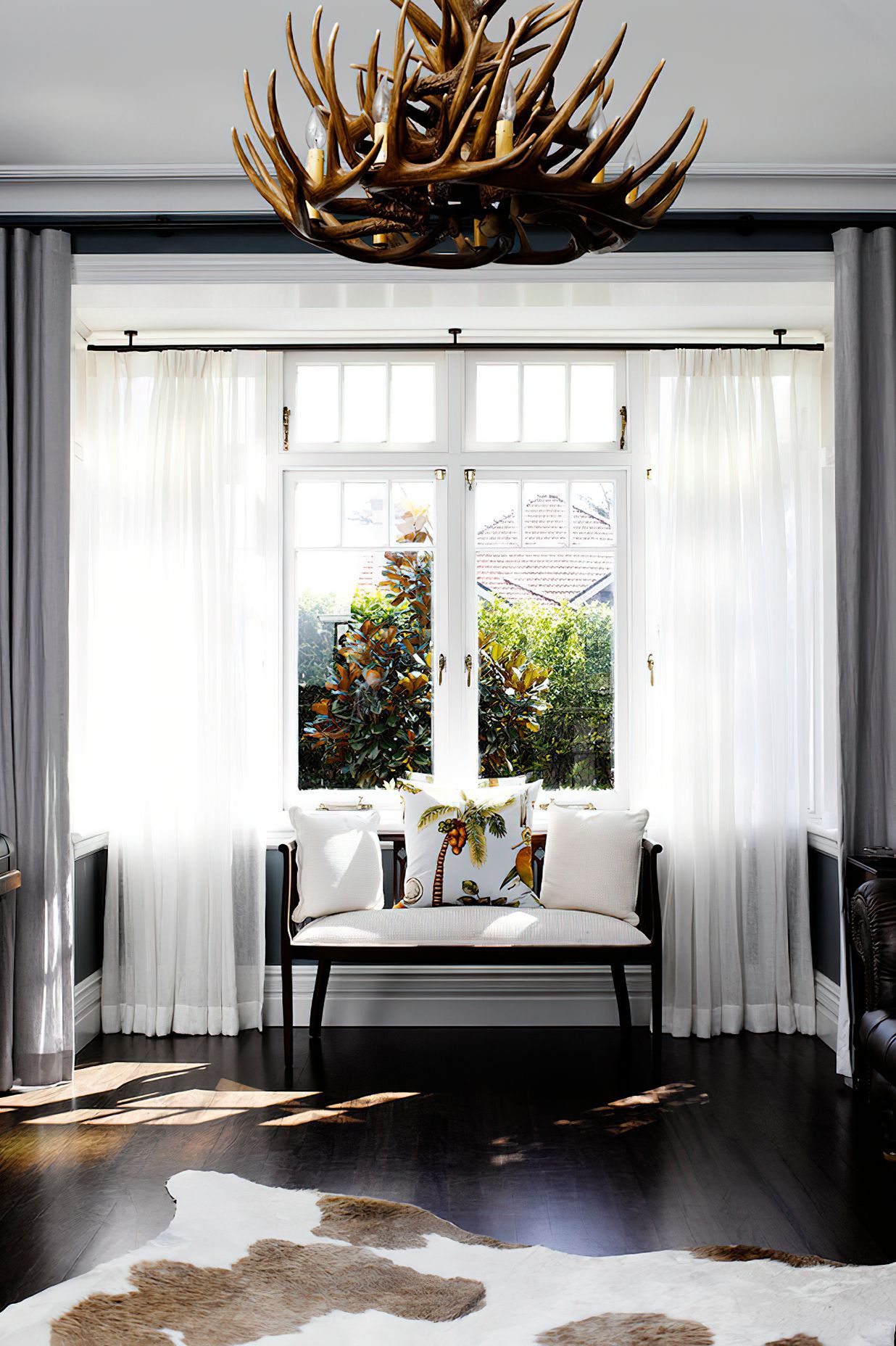 BRITISH COLONIAL STYLE LIVING ROOM - A whimsical window treatment is perfectly paired with the striking elements of this living room.