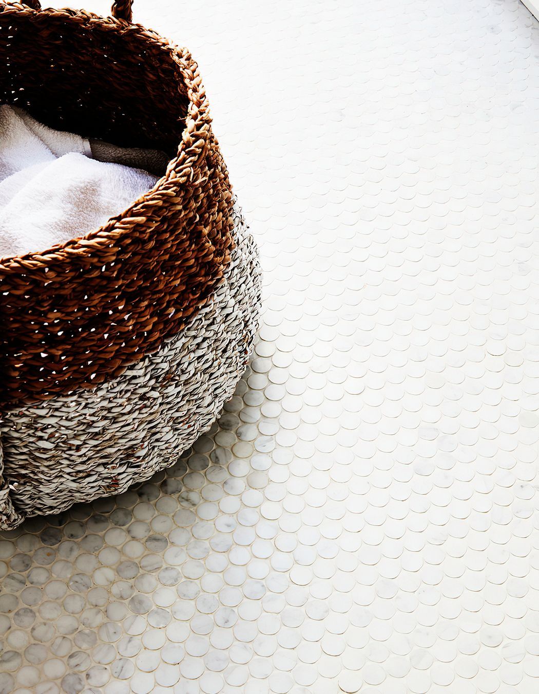 WICKER LAUNDRY BASKET - Mosaic tiles on the laundry floor with a wicker laundry basket.