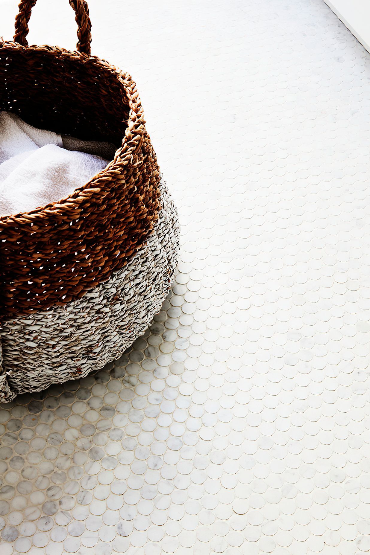 WICKER LAUNDRY BASKET - Mosaic tiles on the laundry floor with a wicker laundry basket.