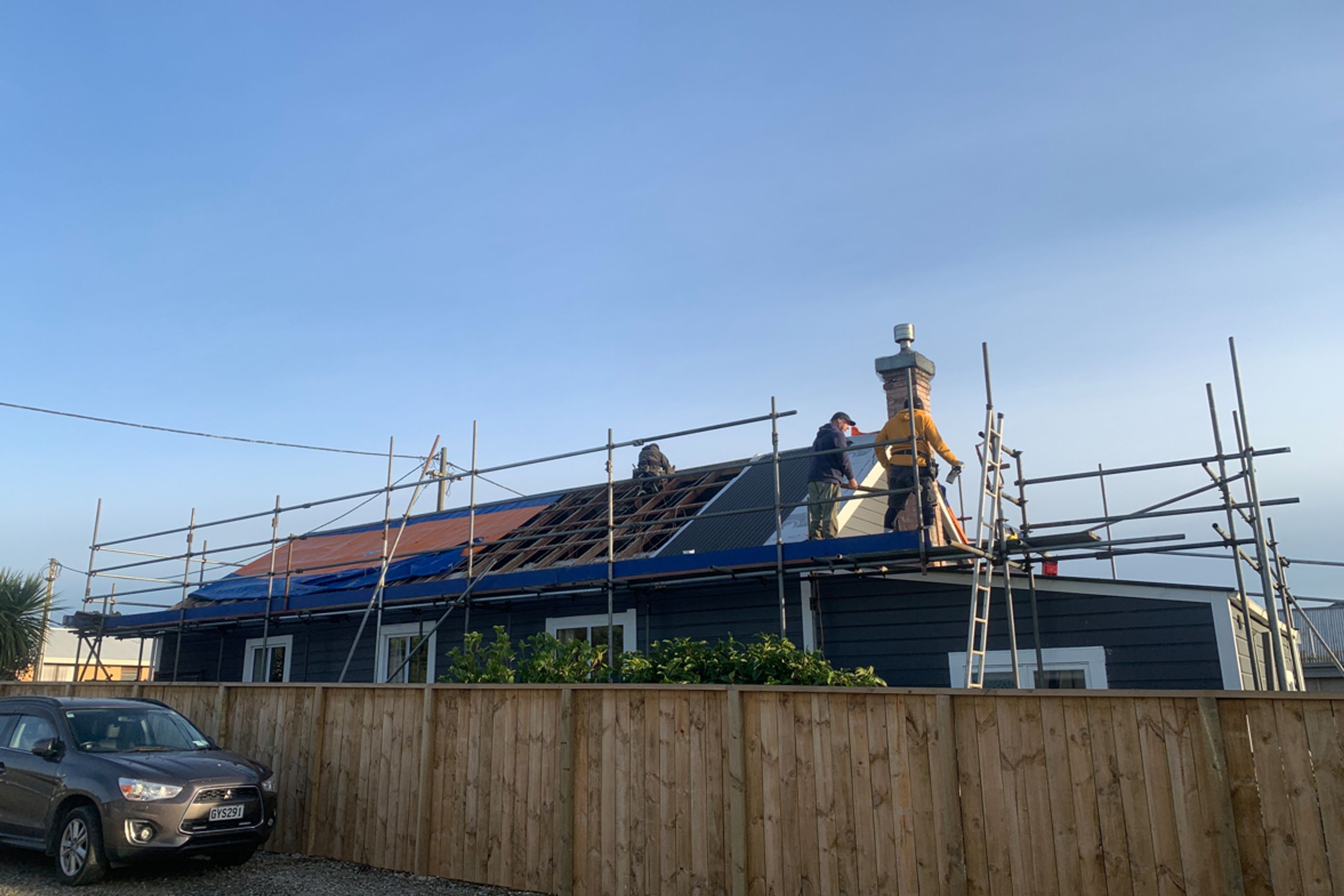 Reroofing underway, taking off the old roofing, repairing any damaged purlins and affixing new roofing underlay and sheets of long run roofing.