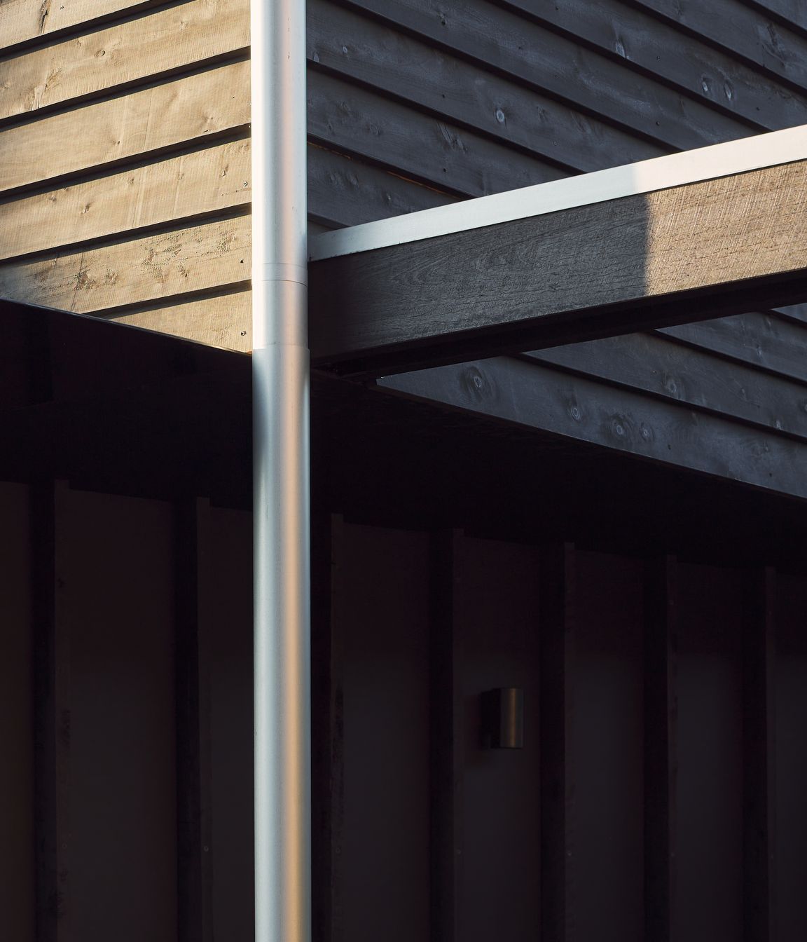 Black stained timber cladding and expressed battens create a muted silhouette for this traditional worker’s cottage, subtly revealing its character and texture throughout the day.⁠