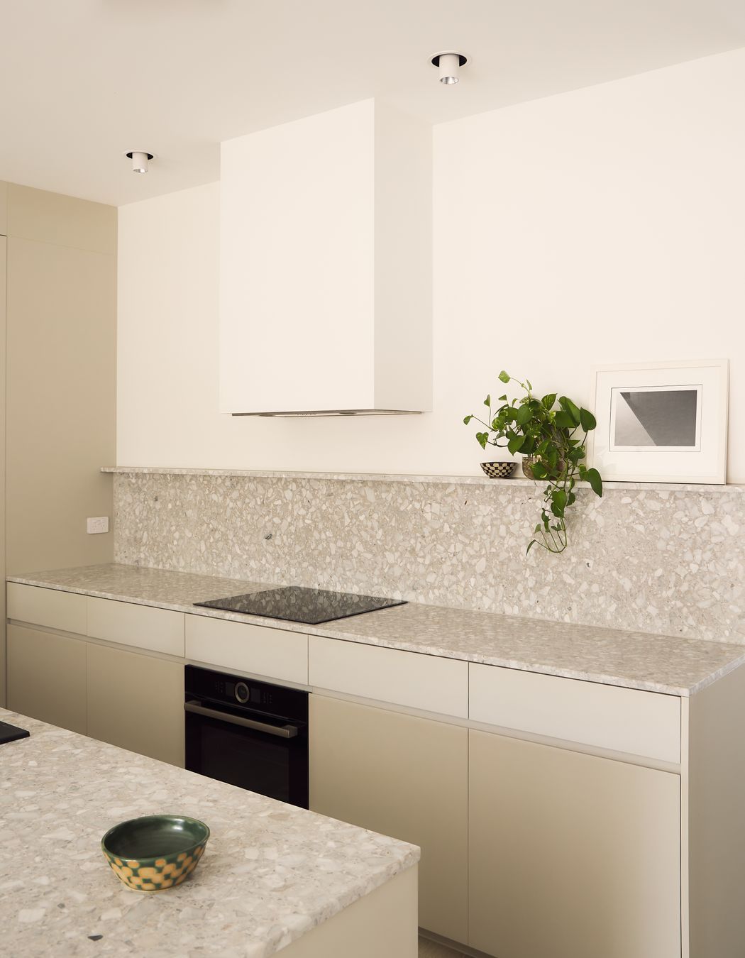 Warm white tones foster a calming ambience in the active lower storey of the house, with textured terrazzo and integrated appliances completing the kitchen and butler’s pantry.
