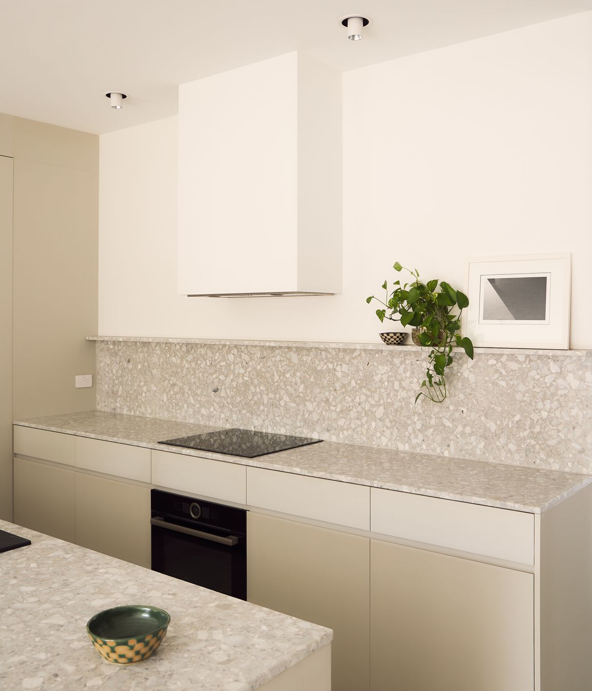 Warm white tones foster a calming ambience in the active lower storey of the house, with textured terrazzo and integrated appliances completing the kitchen and butler’s pantry.