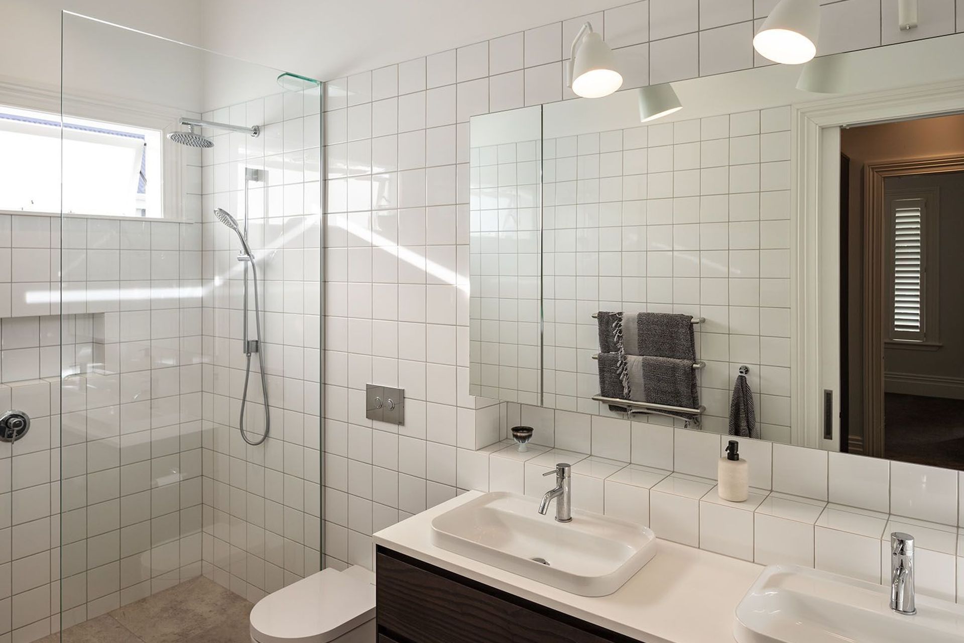 A palette of white tiles and natural materials in the main bathroom, imparts a simple, uncomplicated aesthetic.