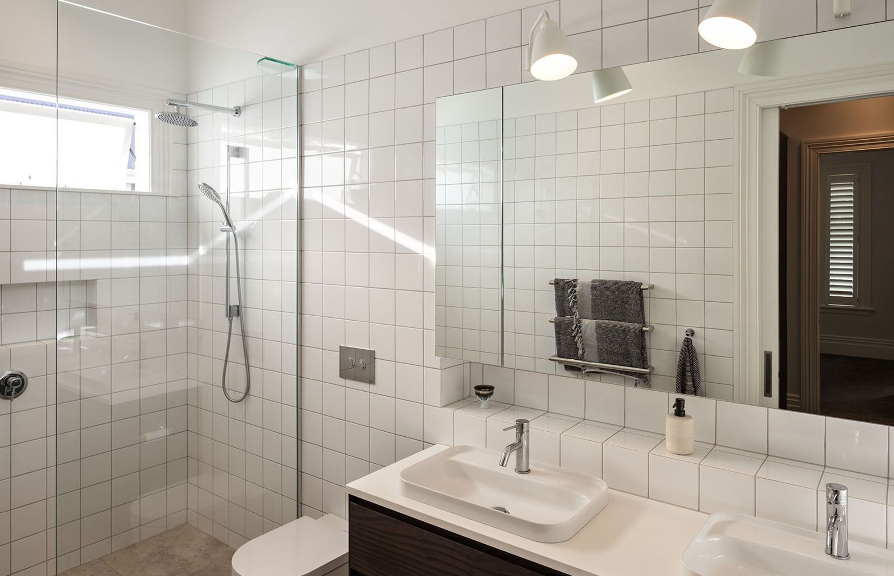 A palette of white tiles and natural materials in the main bathroom, imparts a simple, uncomplicated aesthetic.