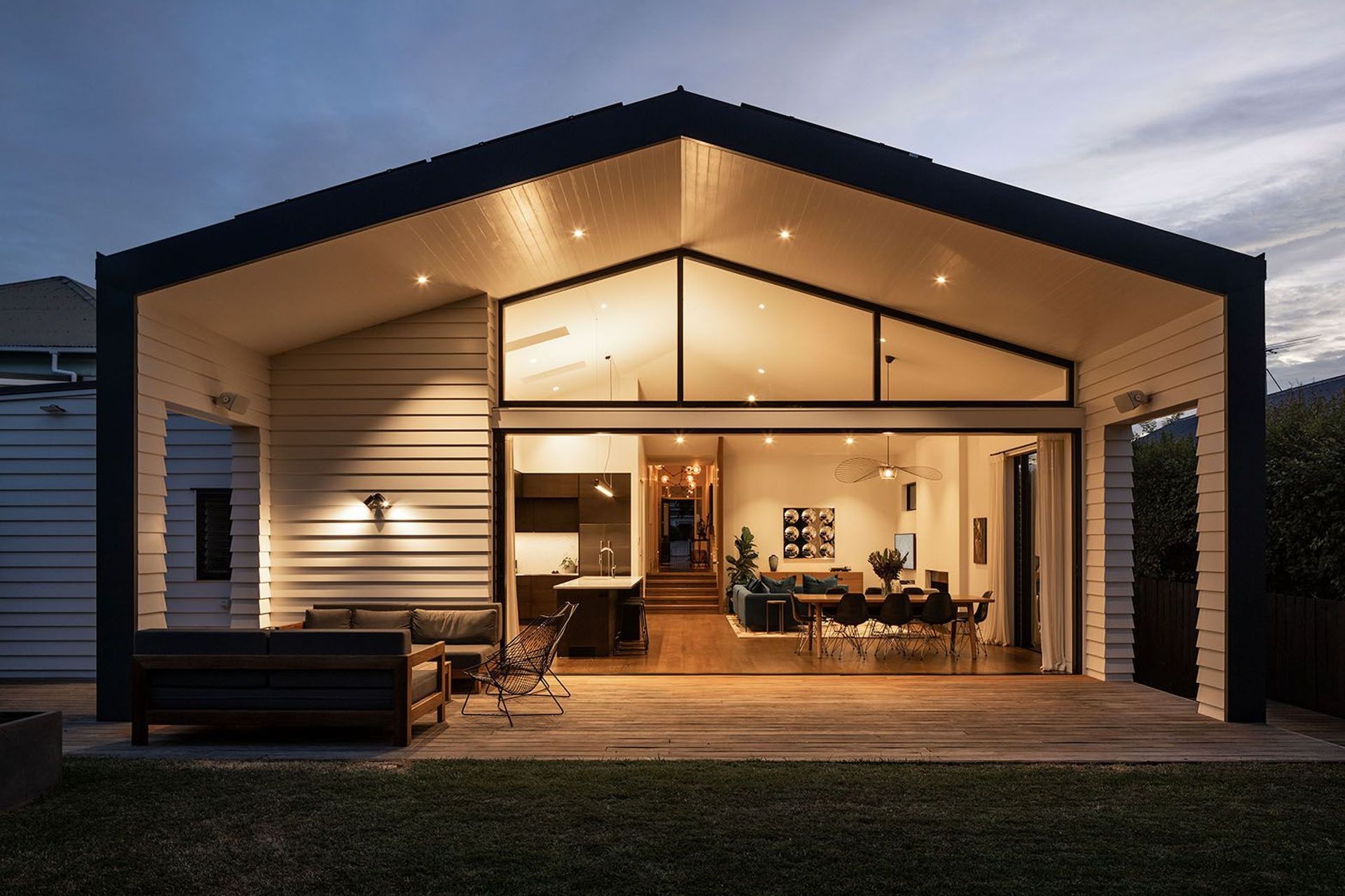 The extended eave creates a sheltered outdoor space while the wall element on the left conceals the sliding door when it's fully open, creating a seamless link between indoors and out.