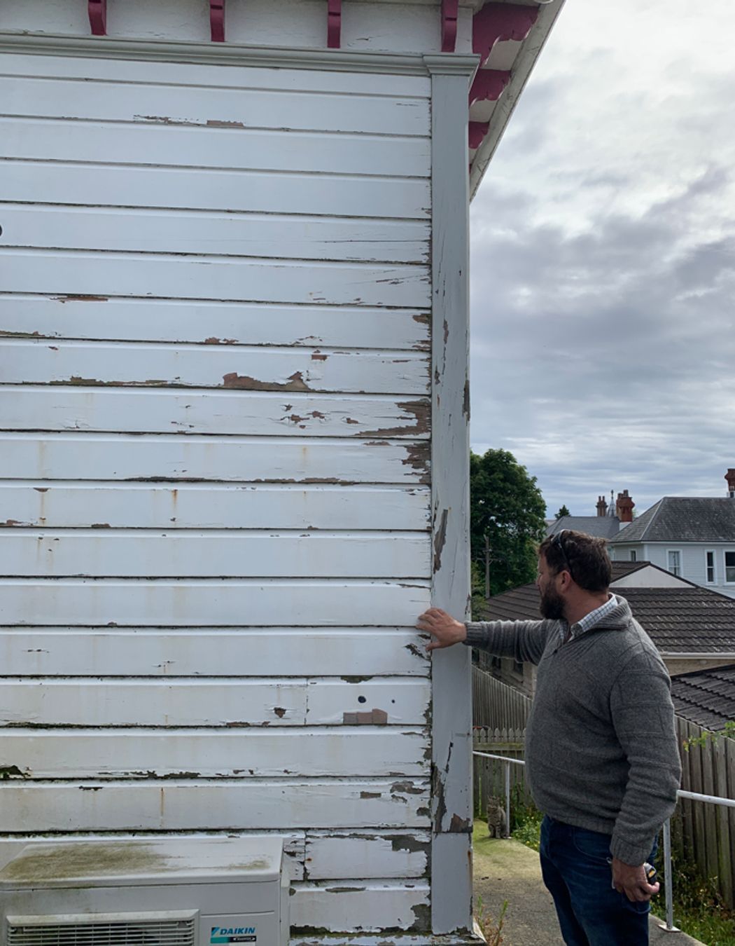 B7-9-Fifield-St-Roslyn-Dunedin-Jeff-inspecting-rotten-weatherboards-at-the-back-of-the-house-before-renovation-JDBuilders.jpg