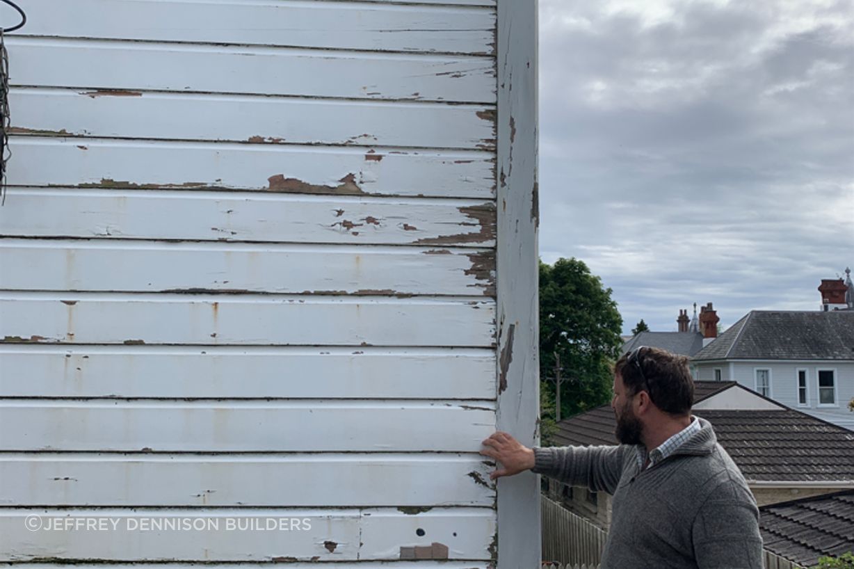 B7-9-Fifield-St-Roslyn-Dunedin-Jeff-inspecting-rotten-weatherboards-at-the-back-of-the-house-before-renovation-JDBuilders.jpg