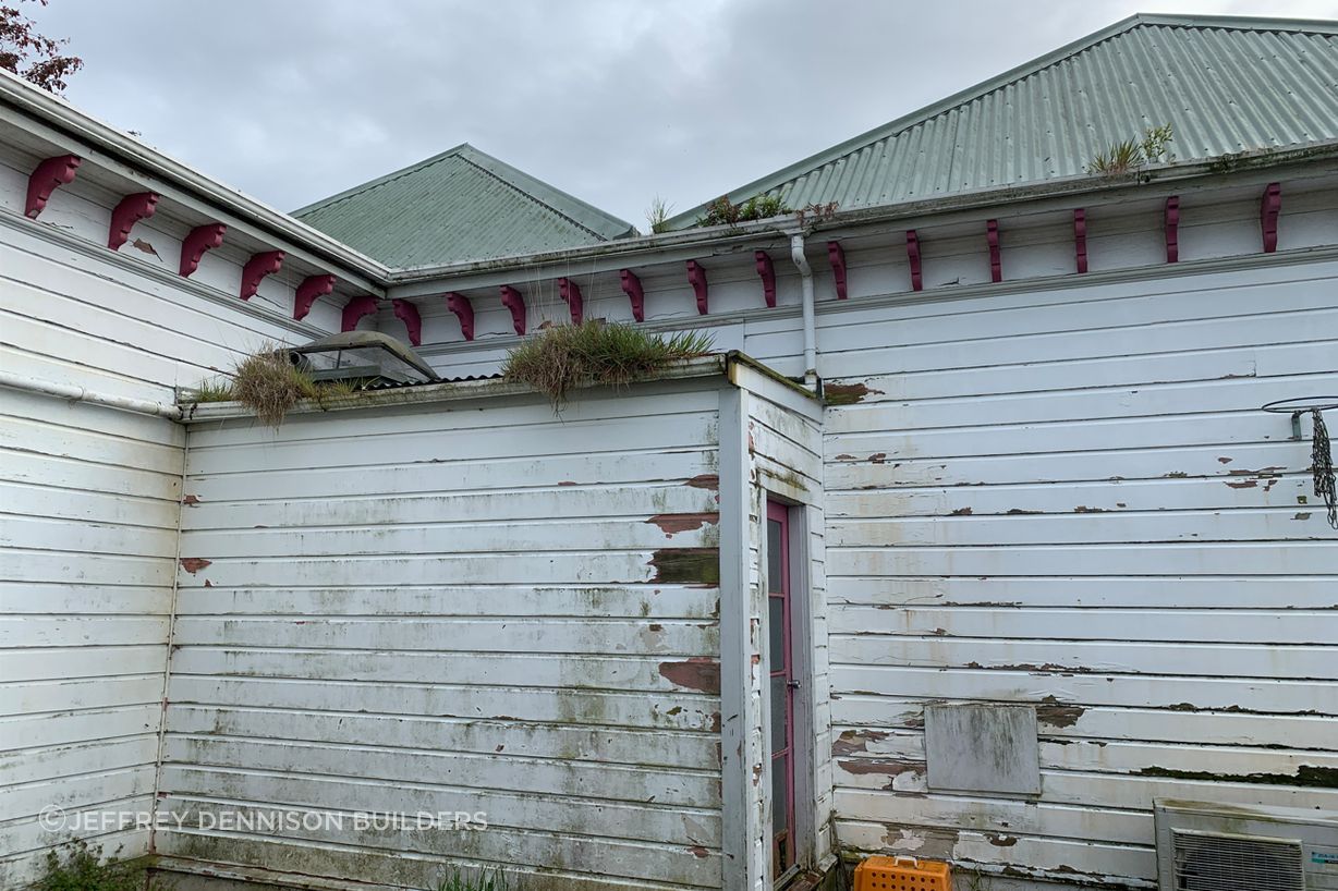 B8-9-Fifield-St-Roslyn-Dunedin-Back-of-the-house-with-grass-growing-from-the-spouting-patched-hole-and-rotten-weatherboards-before-renovation-JDBuildersLR.jpg