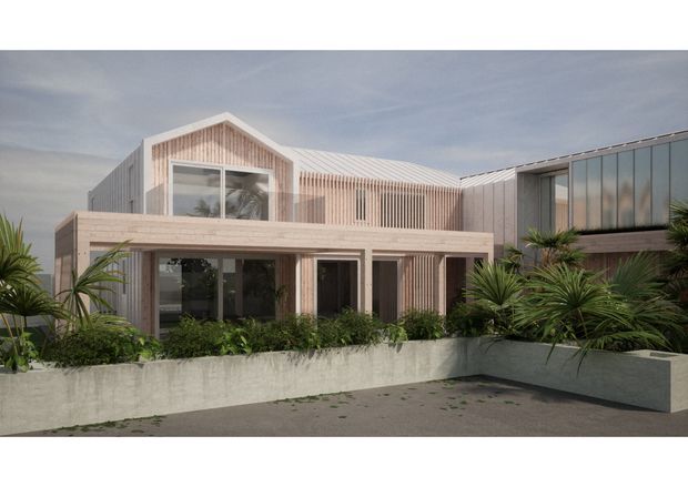 A contemporary multi-level building exterior with a pale timber-clad gabled central volume, projecting covered entry or terrace, extensive glazing, vertical timber screening, and adjoining flat-roofed wing. Dense palms and low planting sit behind angular concrete planter walls in the foreground.