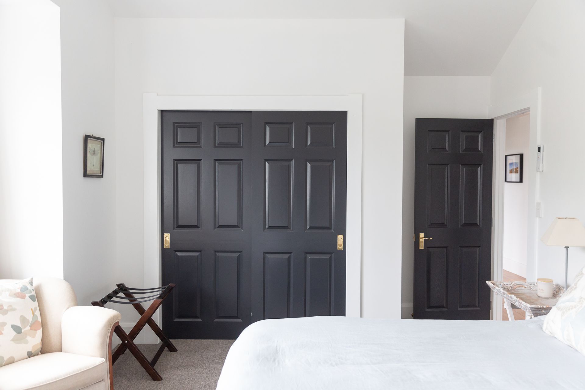 Gorgeous dark painted panelled doors add a little wow factor calm whites of the bedroom.
