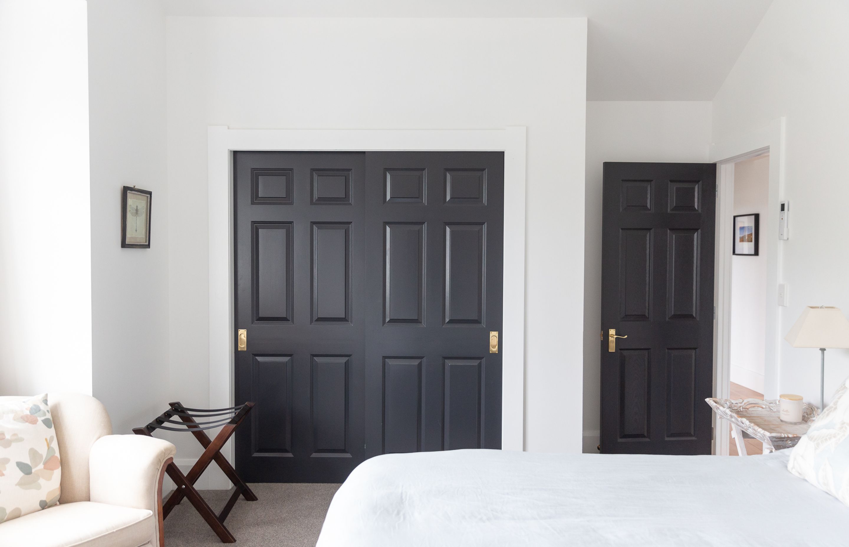 Gorgeous dark painted panelled doors add a little wow factor calm whites of the bedroom.