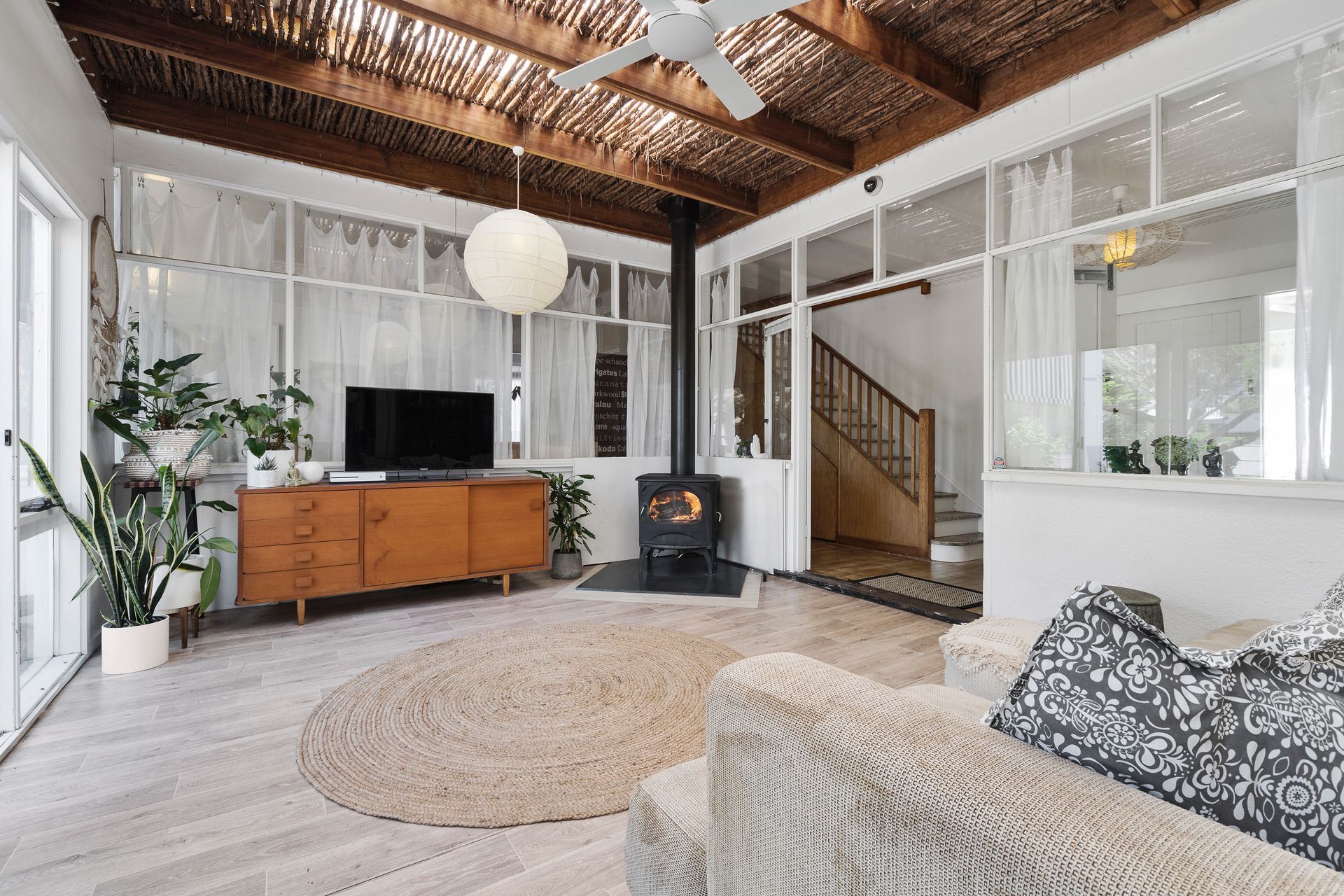 Relax in the cozy living room of Fishermans' Cottage, featuring a driftwood thatched ceiling and a classic Seguin Aurore Cast Iron Fireplace.
