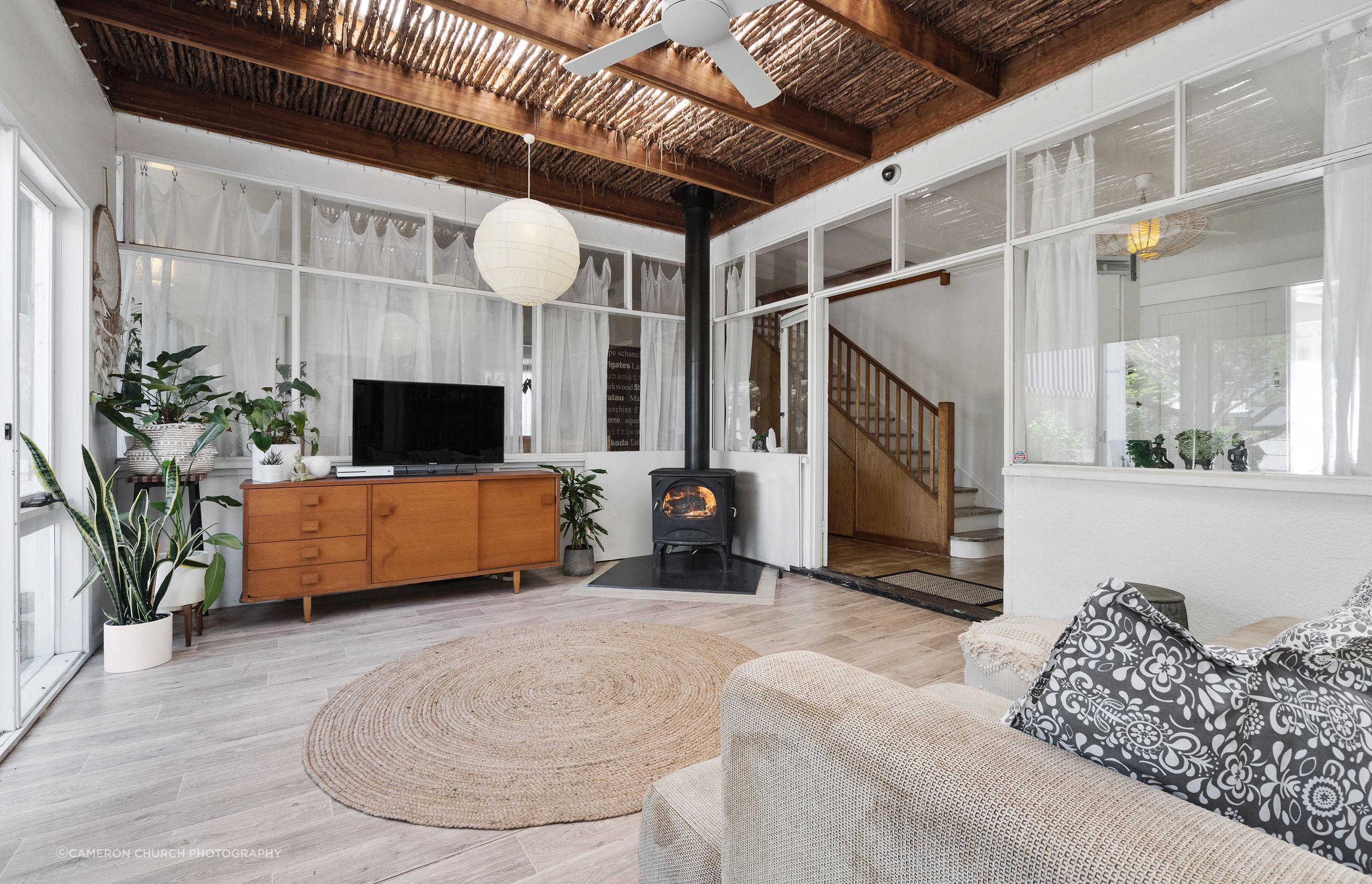 Relax in the cozy living room of Fishermans' Cottage, featuring a driftwood thatched ceiling and a classic Seguin Aurore Cast Iron Fireplace.