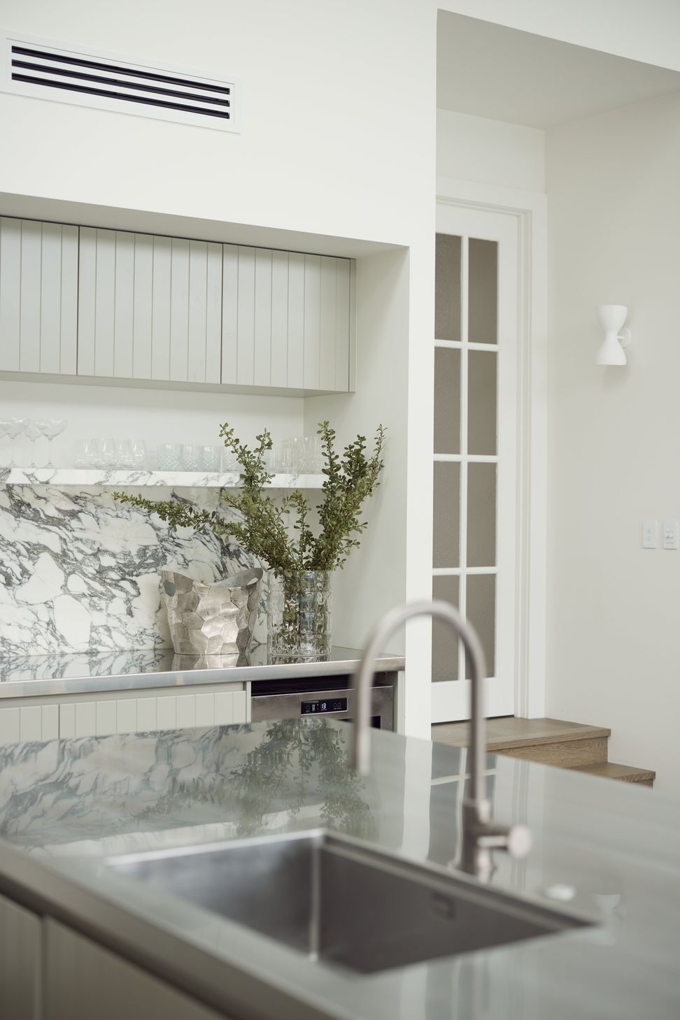 Scullery detail at Point Chevalier Bungalow — Arabescato marble, stainless steel sink and sage cabinetry, with the textured glass French door to the original bungalow just beyond. In collaboration with Hannah Warren Interiors.