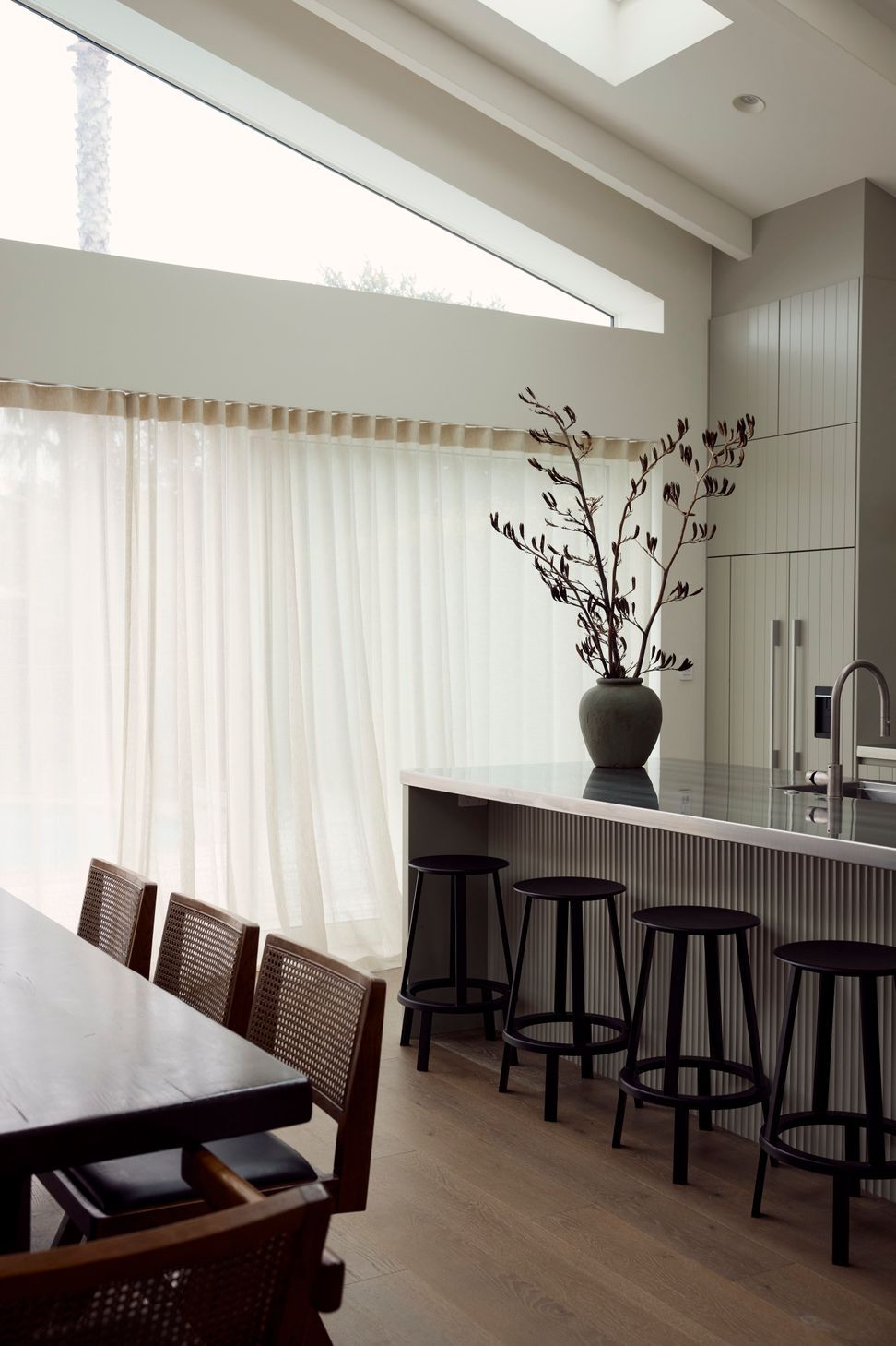 Kitchen and dining in easy conversation — fluted island bench, Arabescato marble and Pierre Jeanneret chairs beneath a soaring skylight. Point Chevalier Bungalow, in collaboration with Hannah Warren Interiors.