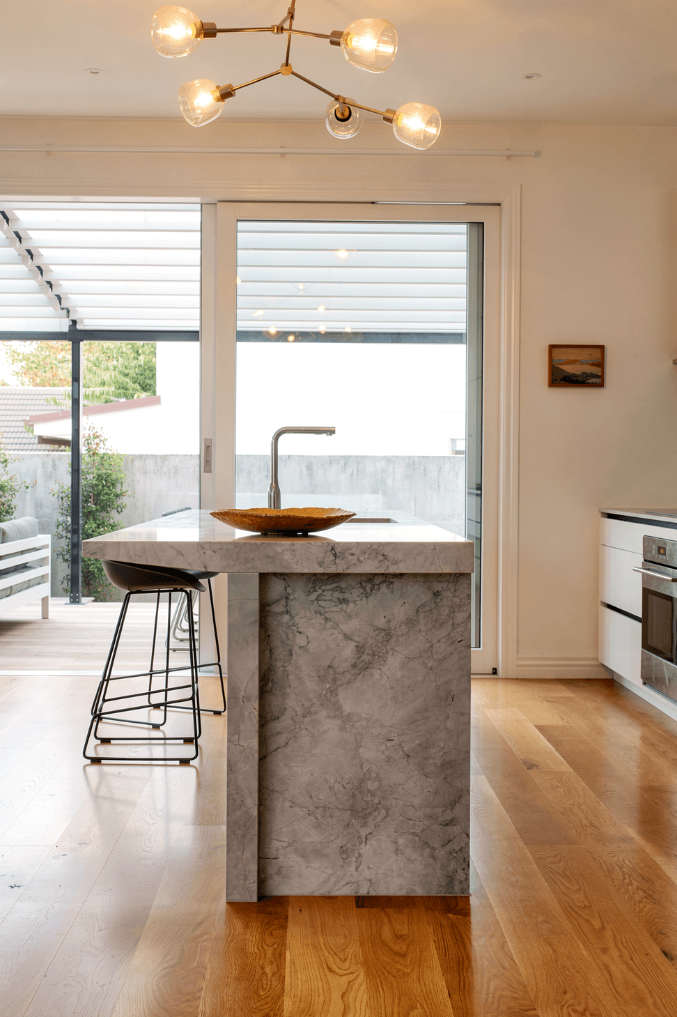 Designed as the social heart of the home, the island encourages gathering from every direction while enhancing workflow and connection to the surrounding living spaces. Its clean lines and natural material palette create a timeless kitchen that balances practicality with understated elegance.