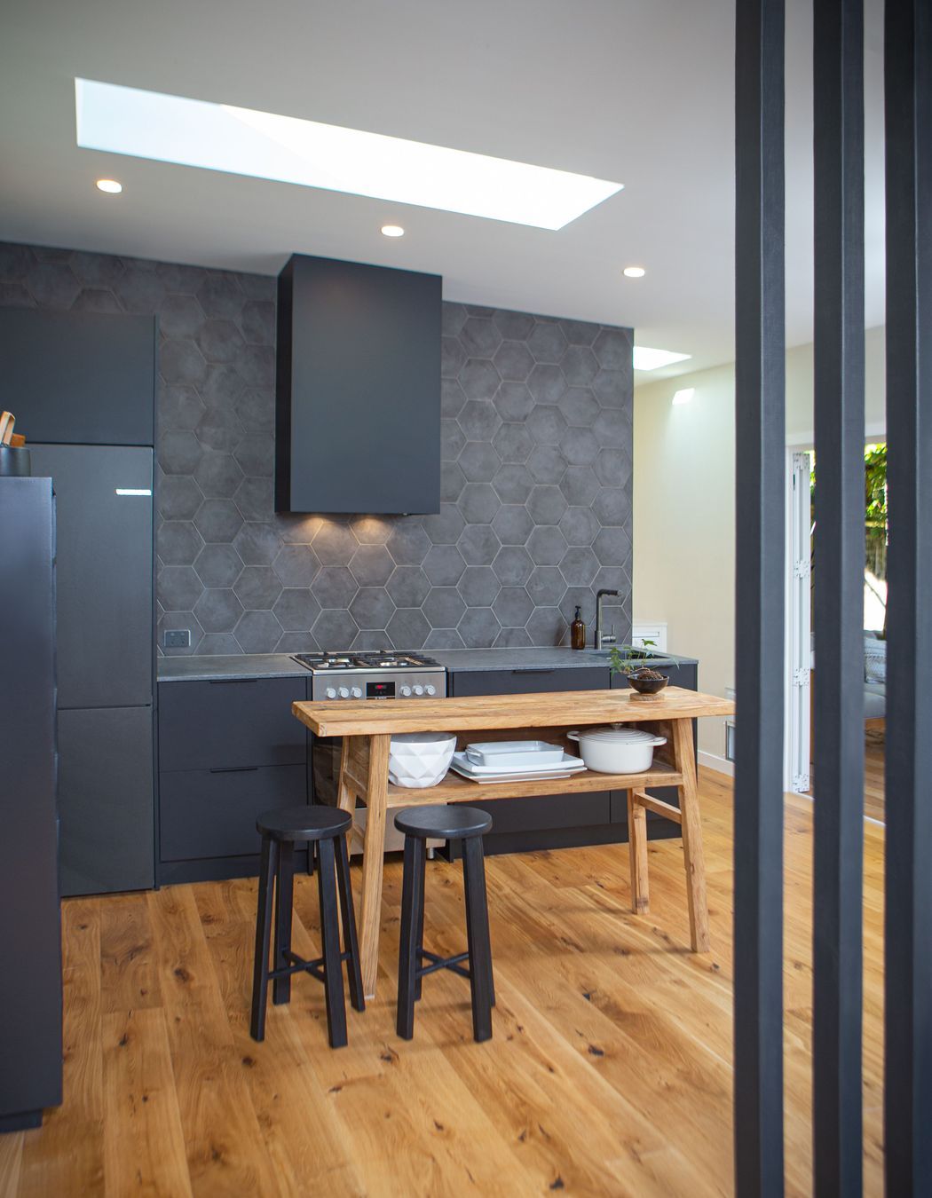 A black floor to ceiling slatted timber screen completes the stair adjacent. Heartwood oak engineered flooring also enhance the dark finishes.