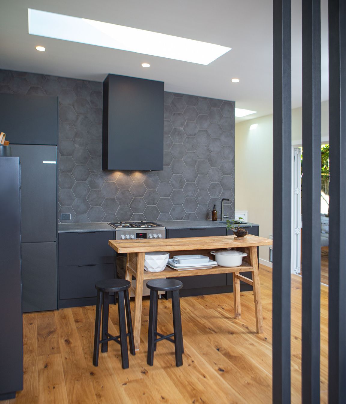 A black floor to ceiling slatted timber screen completes the stair adjacent. Heartwood oak engineered flooring also enhance the dark finishes.