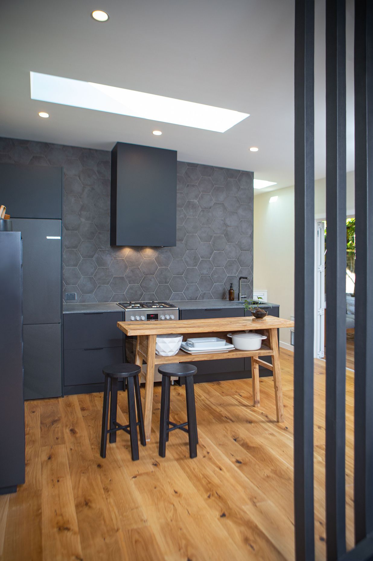 A black floor to ceiling slatted timber screen completes the stair adjacent. Heartwood oak engineered flooring also enhance the dark finishes.