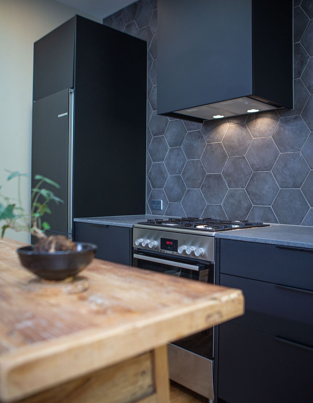 A black rangehood cover or shroud sits well against the grey and black finishes.