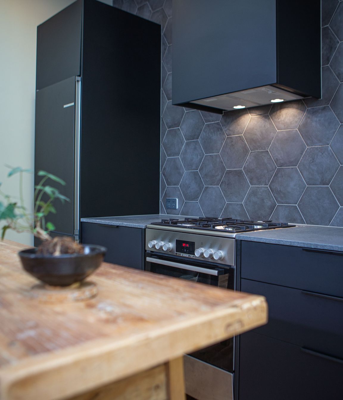 A black rangehood cover or shroud sits well against the grey and black finishes.