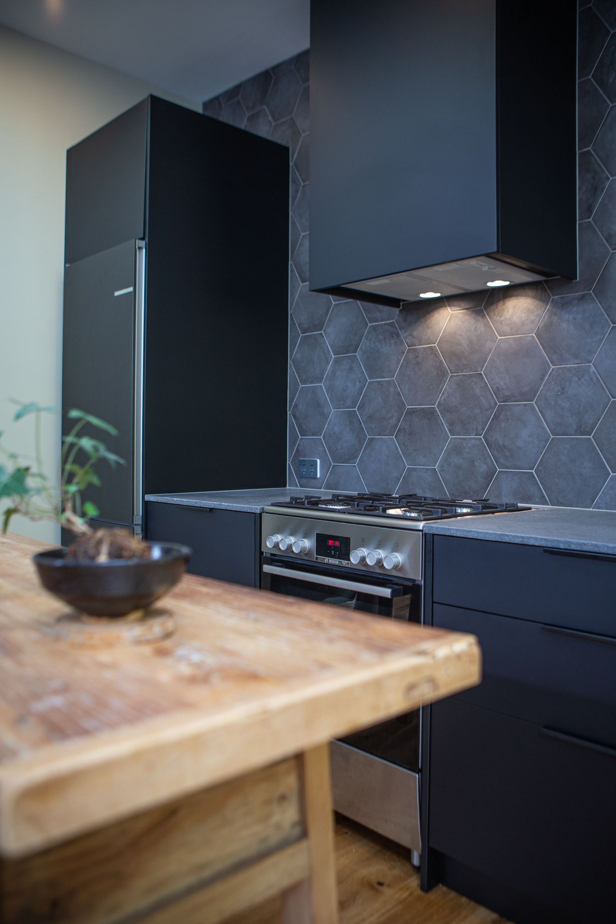 A black rangehood cover or shroud sits well against the grey and black finishes.