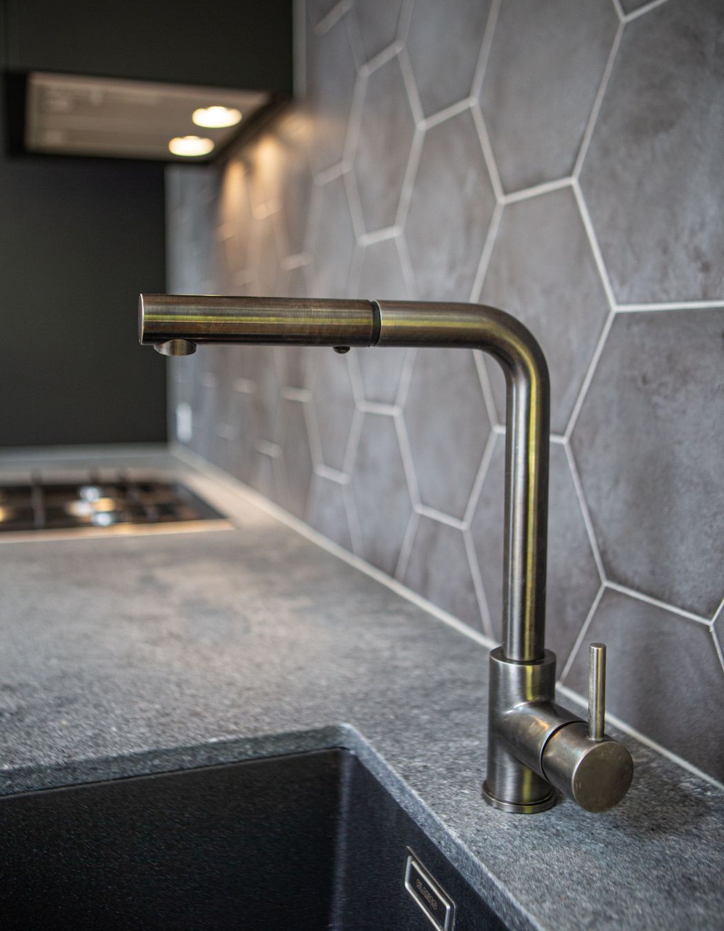 Gun metal kitchen mixer with square spout and Ceasarstone rugged concrete benchtop.