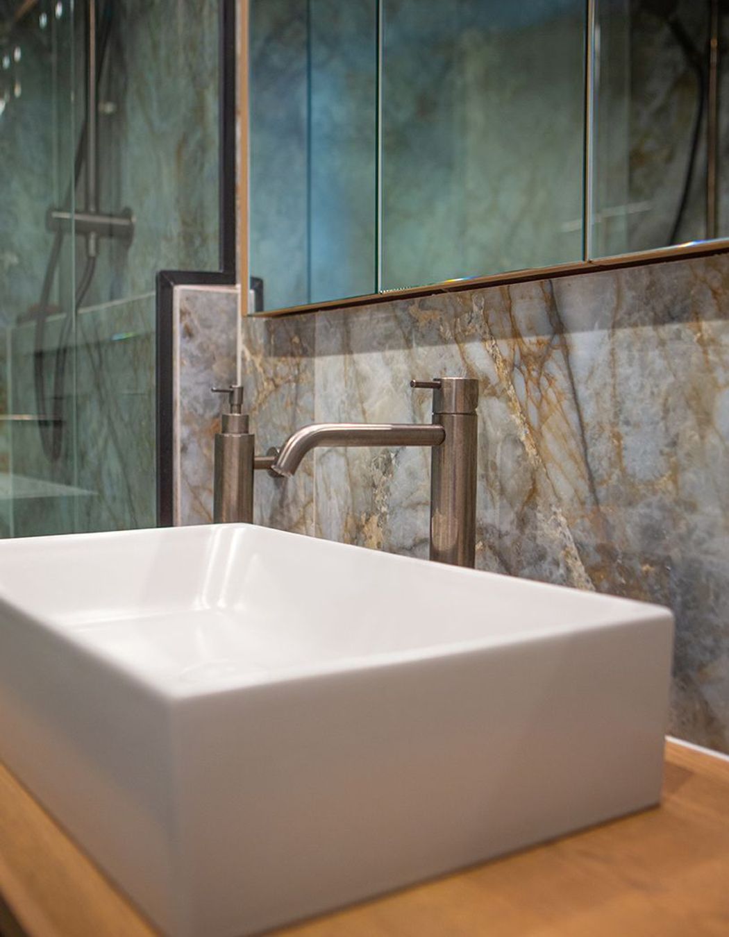 Aged iron wall mounted soap dispenser keeps the counter top clear.