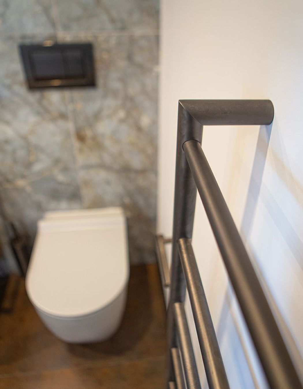 Aged iron heated towel rail and toilet roll holder.