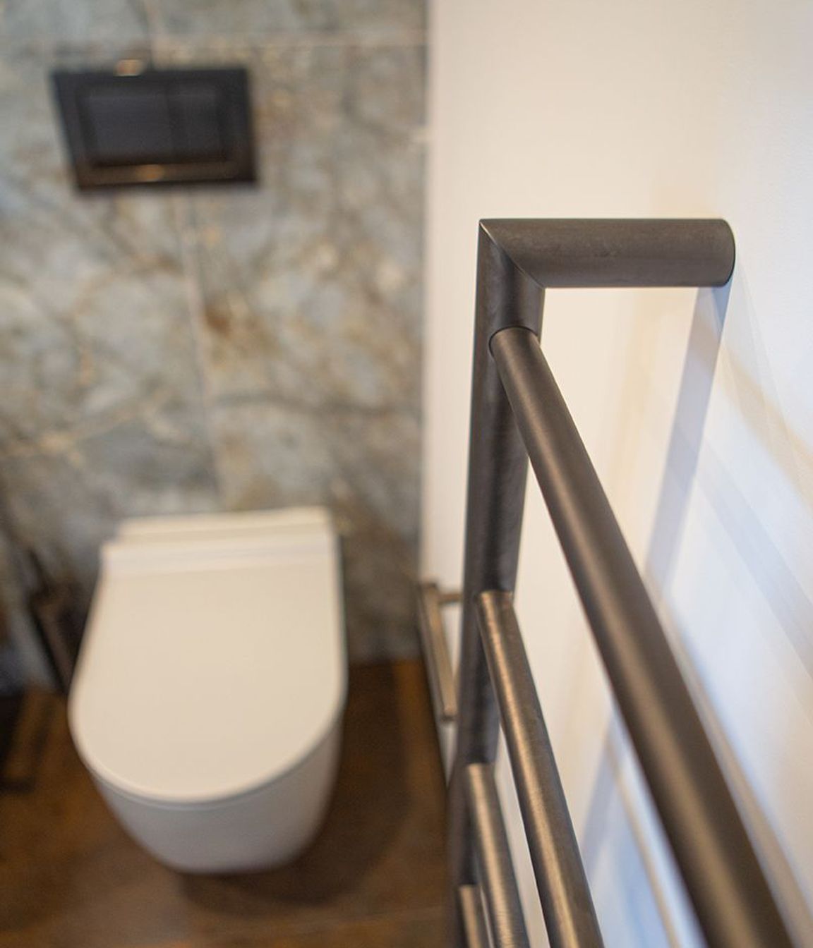 Aged iron heated towel rail and toilet roll holder.