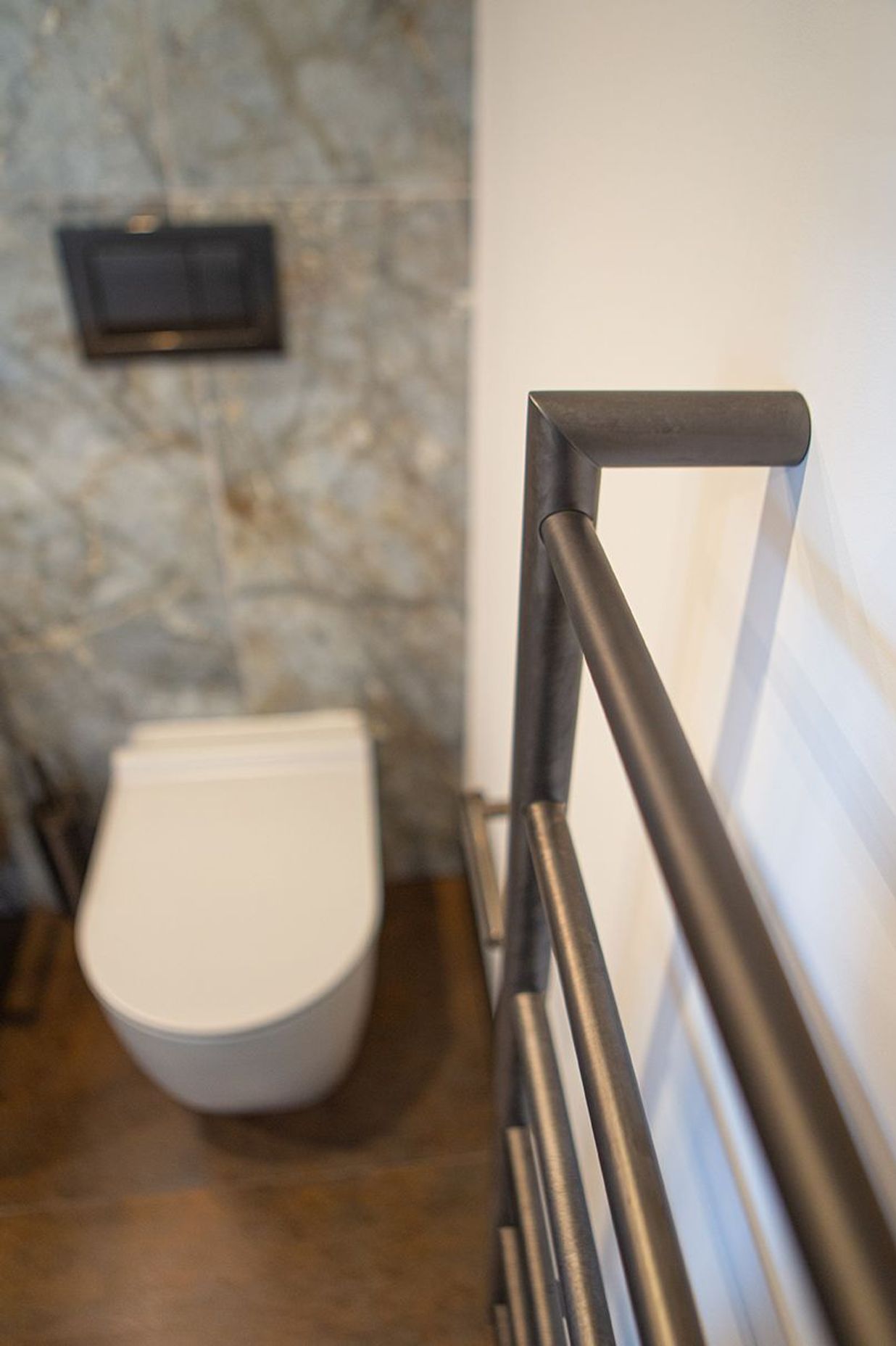 Aged iron heated towel rail and toilet roll holder.