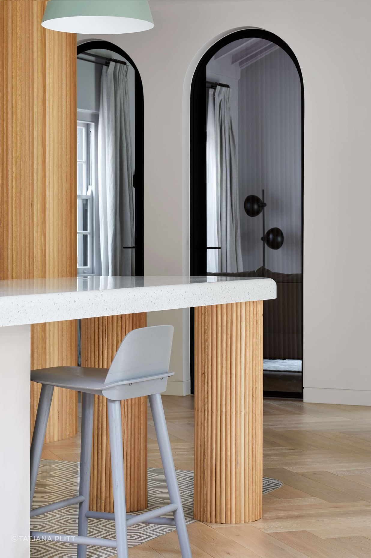 Open concept kitchen with soft pastel coloured finishes featuring cool grey cement hexagon patterned tiles on the floor,  silver birch coloured corian stone bench top and hand crafted oversized pedestal legs using half round dowels as the finish for a contemporary and modern feel. Located in Melbourne, see more from our Arch Deco Project.