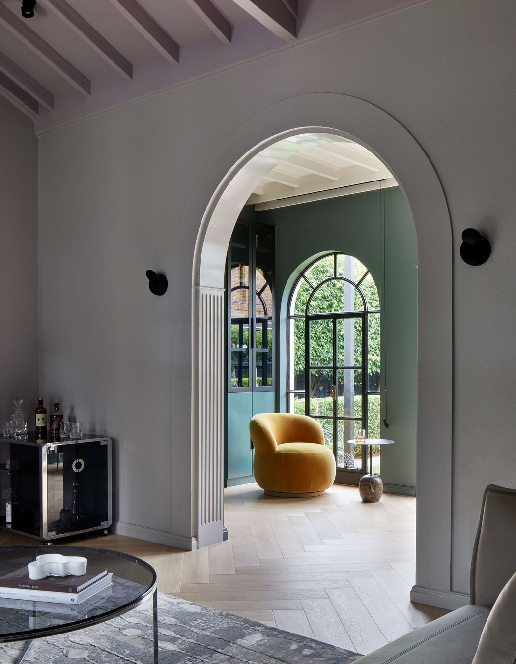 Arches on arches are repeated through this 1930’s art deco spanish mission style house renovation in suburban Melbourne. View through to the library with dark green walls (Paint colour Coriole from Dulux) and an occasional Joy chair in mustard elk velvet from Jardan. See more from our Arch Deco Project.