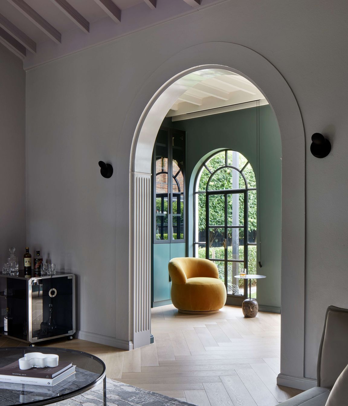 Arches on arches are repeated through this 1930’s art deco spanish mission style house renovation in suburban Melbourne. View through to the library with dark green walls (Paint colour Coriole from Dulux) and an occasional Joy chair in mustard elk velvet from Jardan. See more from our Arch Deco Project.